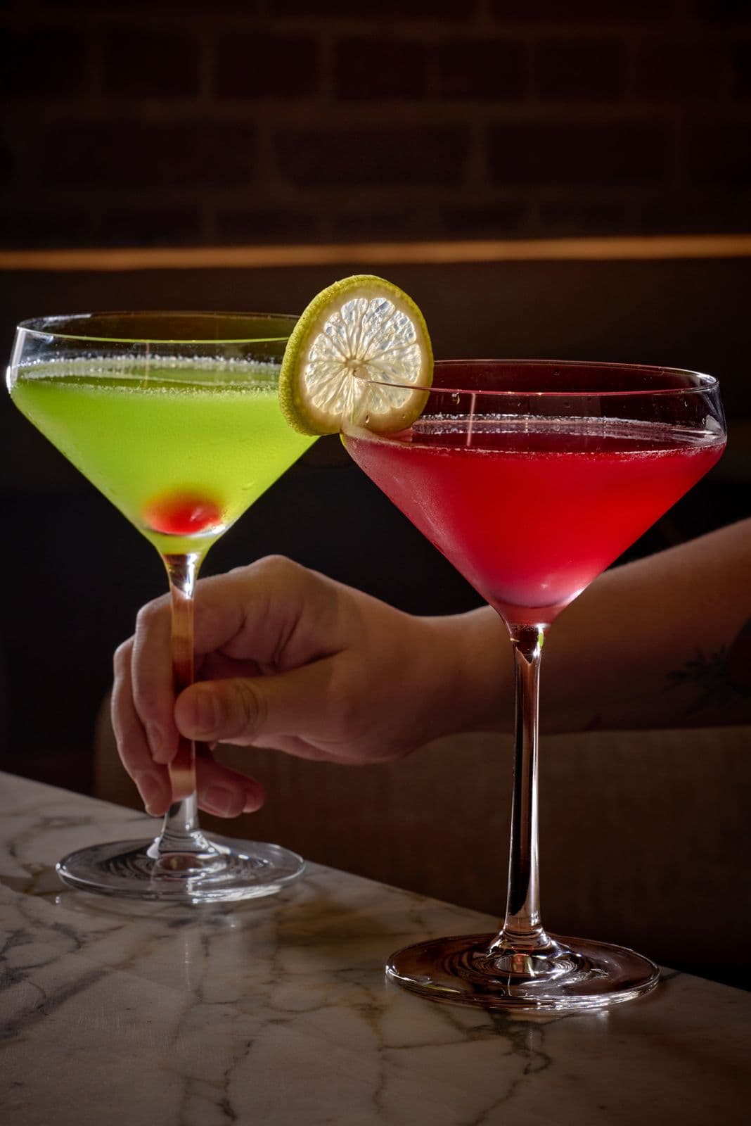 Un Mexican Slipper y un Cosmopolitan en copa de martini sobre la barra de mármol