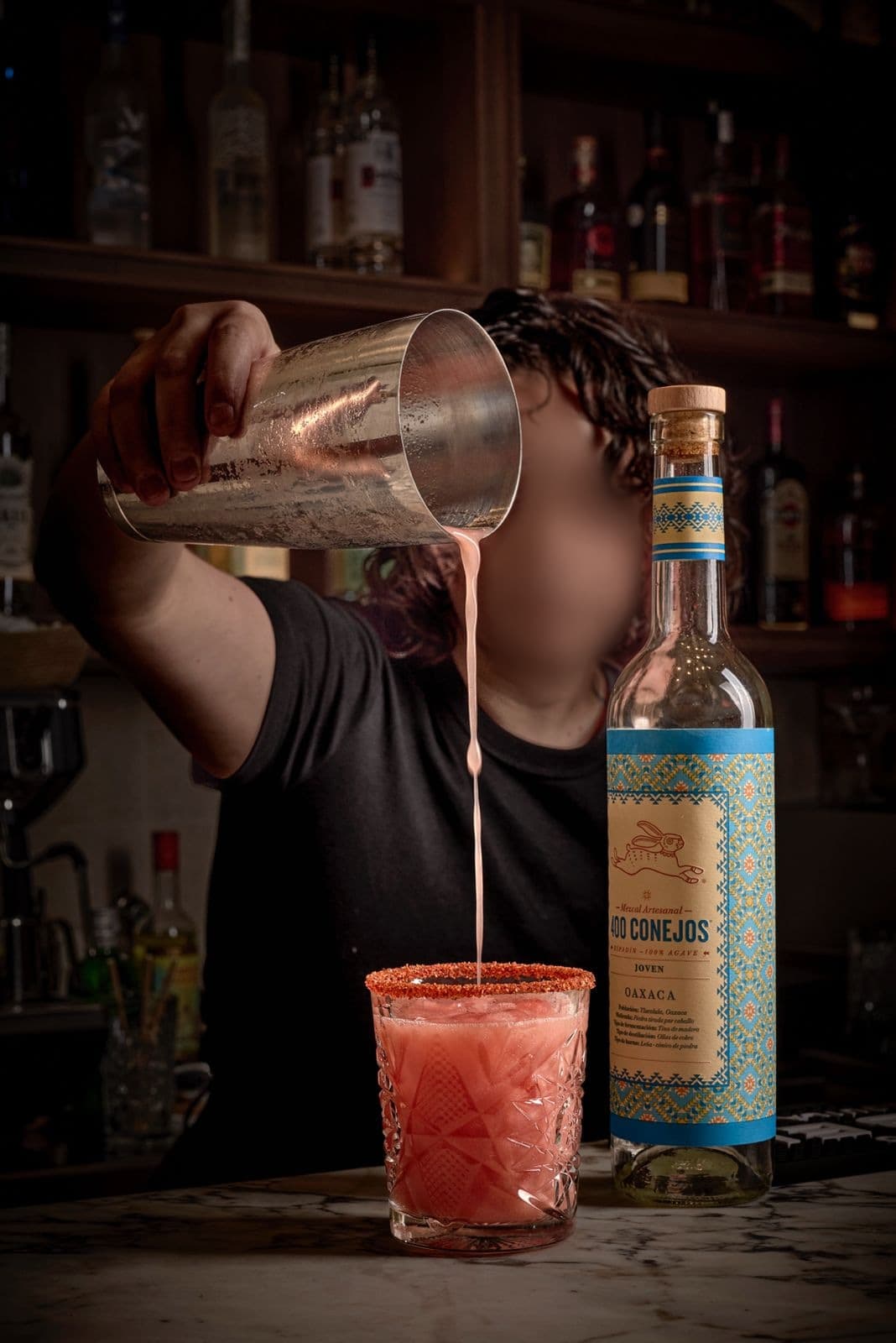 Mezcalita Tío Teddy con borde de chile, servida junto a una botella de mezcal